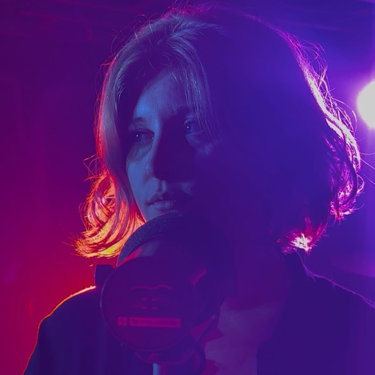 Maggie Moon singing under violet and blue stage lights